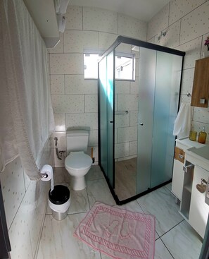 A bathroom with a toilet, bidet, and a shower area with a glass door. - Apart ZSS (Penha)