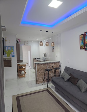 A modern kitchen with a central island, bar stools, and pendant lighting. - Apart ZSS (Penha)