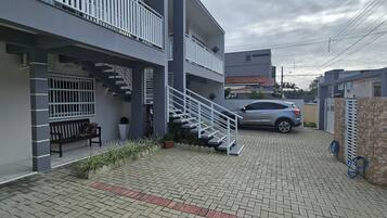 Um edifício moderno com uma escadaria, um carro estacionado em frente e um caminho de acesso pavimentado.