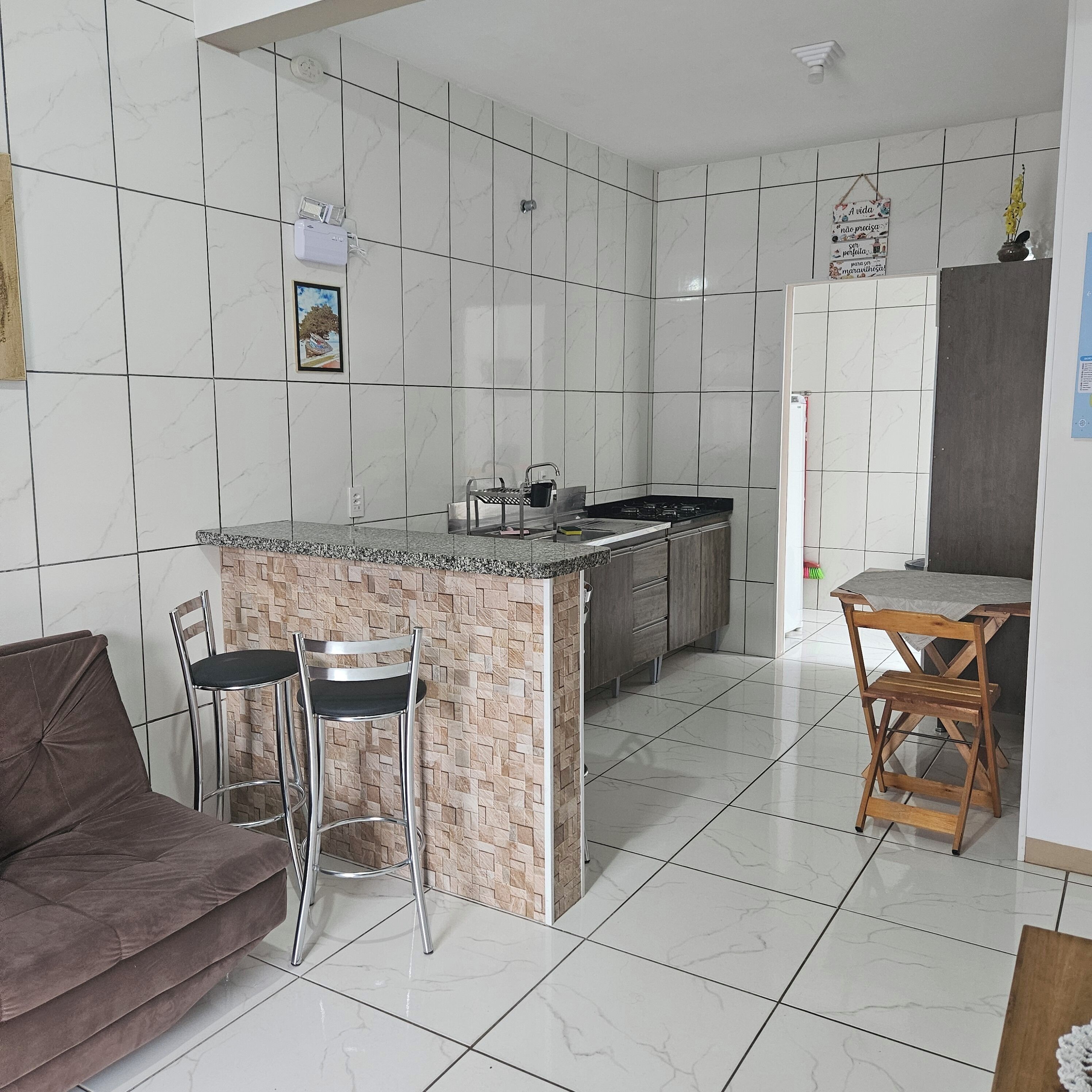 Uma cozinha moderna com painel de parede em mármore, ilha integrada com assentos e área de jantar com mesa e cadeiras.