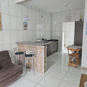 A modern kitchen with a marble backsplash, a built-in island with seating, and a dining area with a table and chairs. - Apart ZSS (Penha)