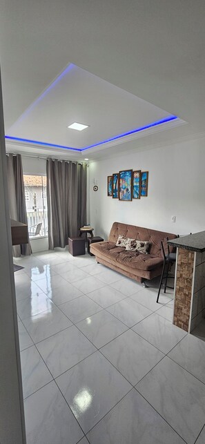 A modern living room with a sofa, a coffee table, and a dining area with a table and chairs. - Apart ZSS (Penha)