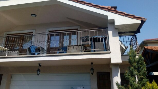 A two-story house with a balcony, a garage, and a small tree in the front yard. - Monika apartman (Velky Meder)