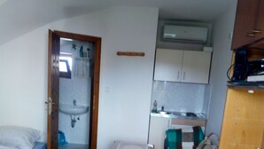 A compact room with a bed, a small table, a sofa, a kitchenette, and a bathroom. - Monika apartman (Velky Meder)