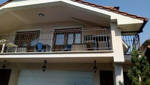 A two-story house with a balcony, a garage, and a tiled roof. - Monika apartman (Velky Meder)