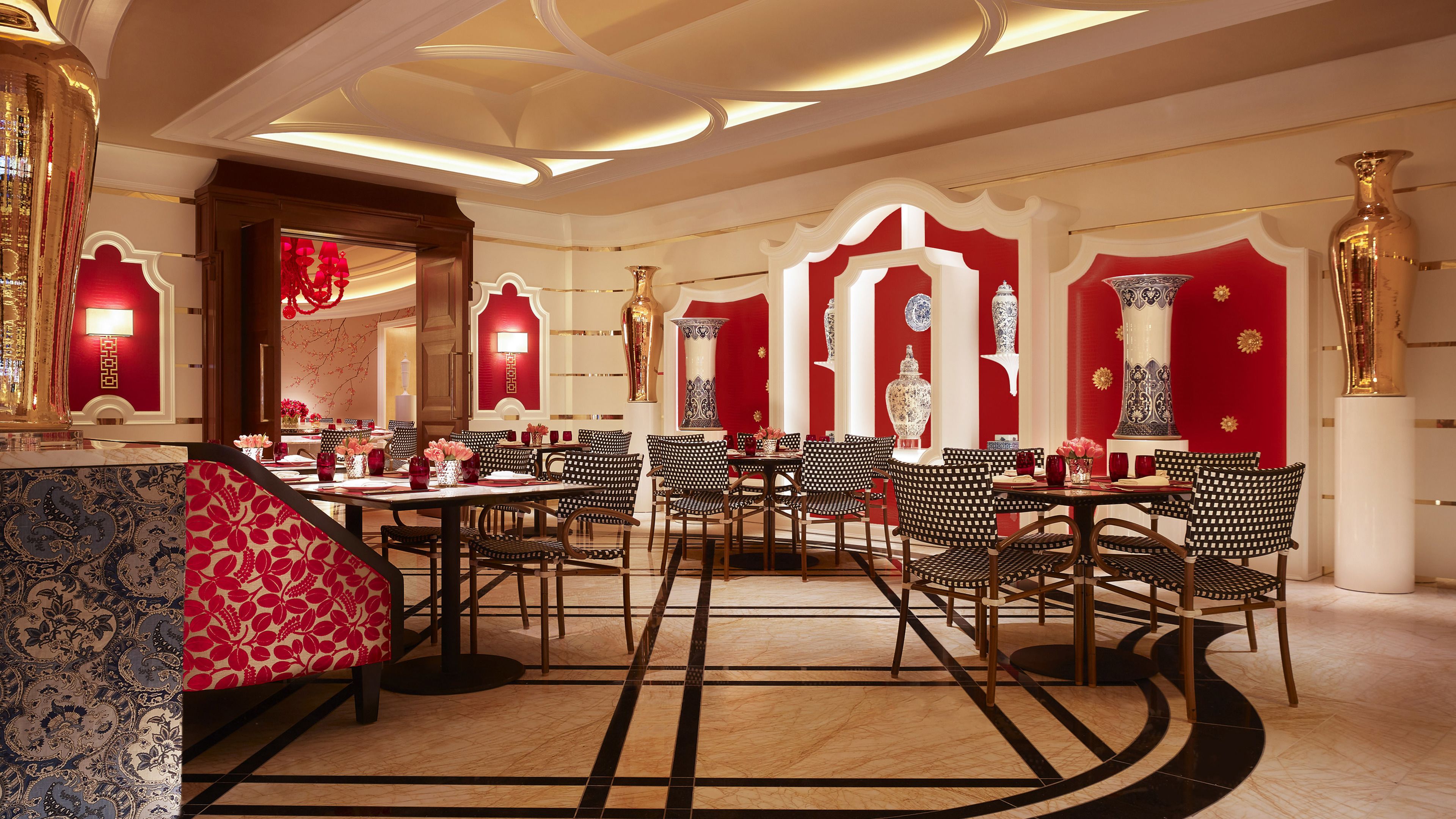 A restaurant with a modern interior, featuring black and white patterned chairs, red and white decor, and a marble floor.
