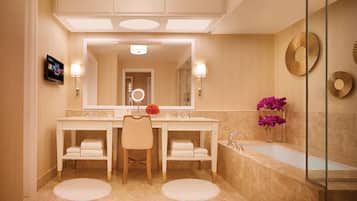 Un baño moderno con dos lavamanos, una silla, un espejo grande, un tocador, una bañera y apliques decorativos de pared.