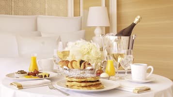 Une table dressée pour le petit-déjeuner, avec des crêpes, des croissants et un bouquet de fleurs.