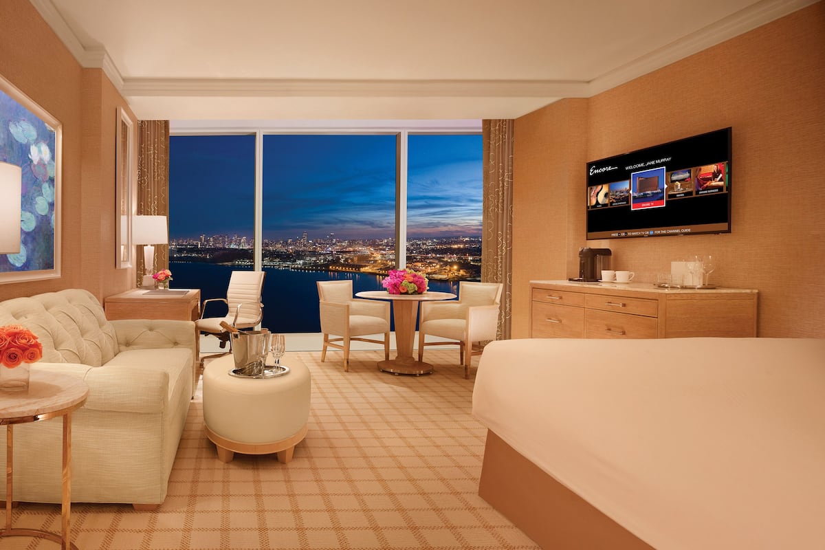 Una habitación de hotel con vista a la ciudad, televisión, escritorio, sofá, sillón y cama.