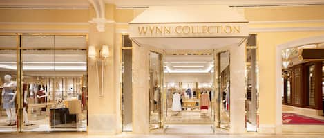 The entrance of the Wynn Collection hotel with a grand marble facade, mannequins displaying clothing, and a red carpet leading inside.
