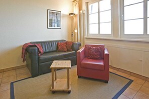 A living room with a sofa, a chair, a small table, a lamp, and a window. - House Martha - Ruth - House Martha (Ahrenshoop)