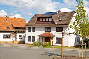 A two-story building with a brown tiled roof, a small balcony with flowers, and a sign indicating it is a restaurant. - Apartment 2 - Apartment "am-edersee" (Edertal)