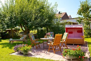 A patio area with a wooden table, chairs, a small sofa, and a striped canopy. - Apartment 2 - Apartment "am-edersee" (Edertal)