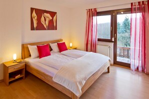 A bedroom with a large bed, two bedside tables, a nightstand, a radiator, and a window with curtains. - Apartment 2 - Apartment "am-edersee" (Edertal)