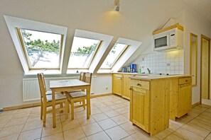 A kitchen with skylights, wooden cabinets, and a dining table.