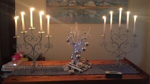 Une table à manger avec un set de table, un centre de table décoratif et un chandelier avec des bougies allumées.