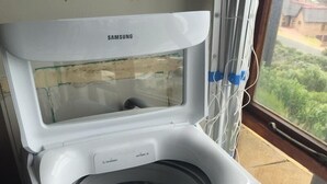 Un lave-linge Samsung doté d’une porte transparente, d’un panneau de commande et d’une fenêtre située au-dessus de la porte.
