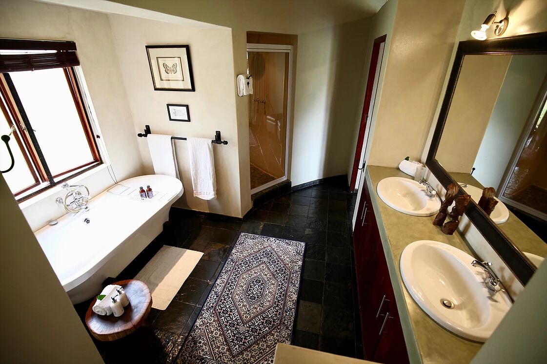A bathroom with a bathtub, two sinks, a large mirror, and a shower area.