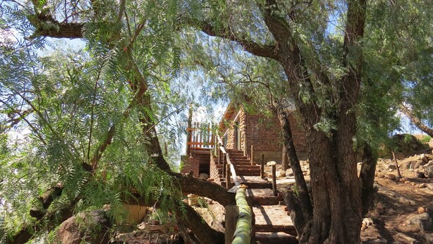 A rustic stone building with a wooden staircase leading up to a balcony.