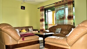 A living room with two leather sofas, a coffee table, and a ceiling fan. - Fastcare Luxury Apartments/Villas (Mtwapa)