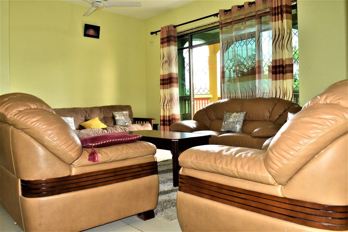 A living room with two leather sofas, a coffee table, and a ceiling fan.