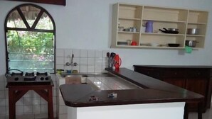 A kitchen with a central island, a built-in oven, and a window with a view of greenery. - Fastcare Luxury Apartments/Villas (Mtwapa)