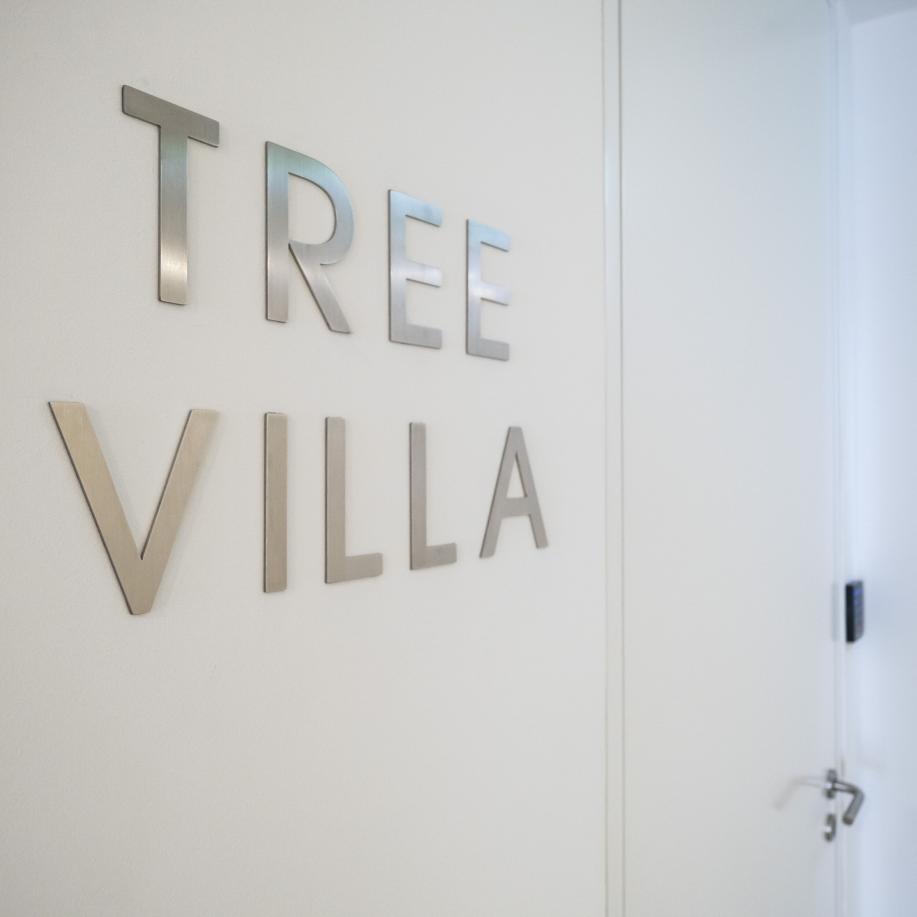 Una pared con las palabras "TREE VILLA" en letras metálicas.