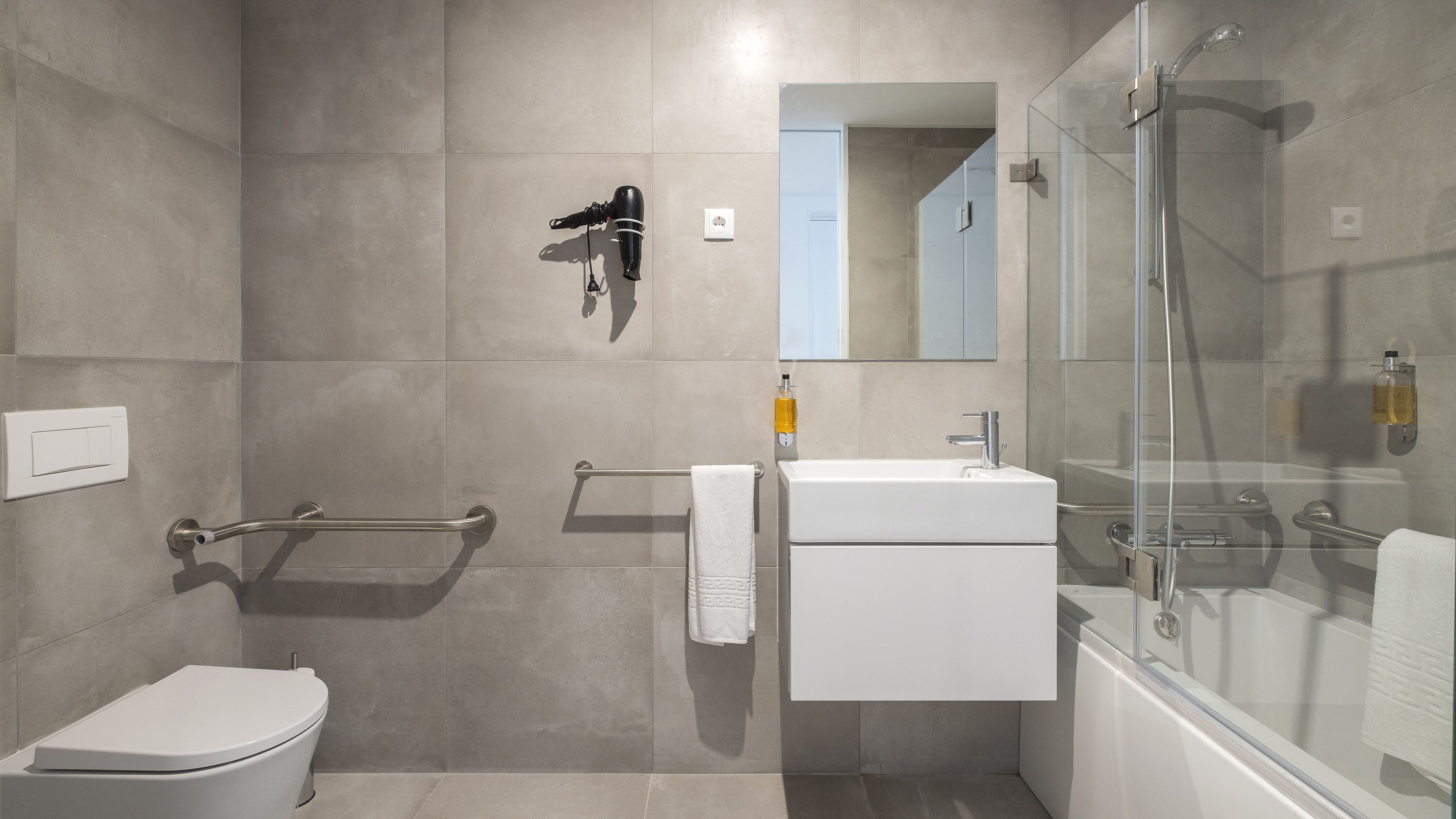 A modern bathroom with a toilet, vanity, and shower area.