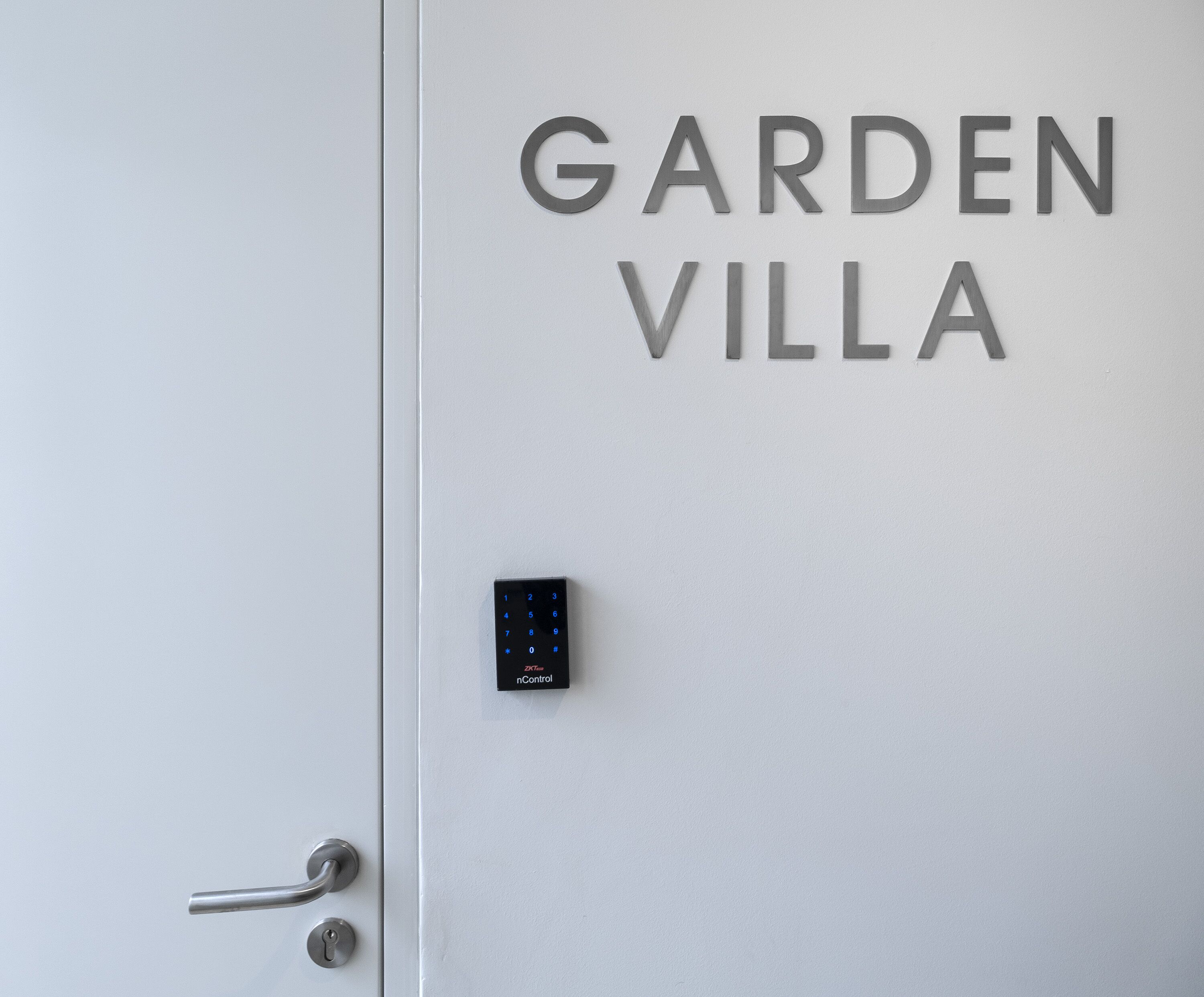 Une porte sur laquelle on peut lire les mots « GARDEN VILLA » et qui est équipée d’un système de verrouillage à clavier.