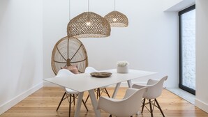 A modern dining area with a white table, four white chairs, and two hanging pendant lights. - Aqua - Pópulo Eco Village (Ponta Delgada)