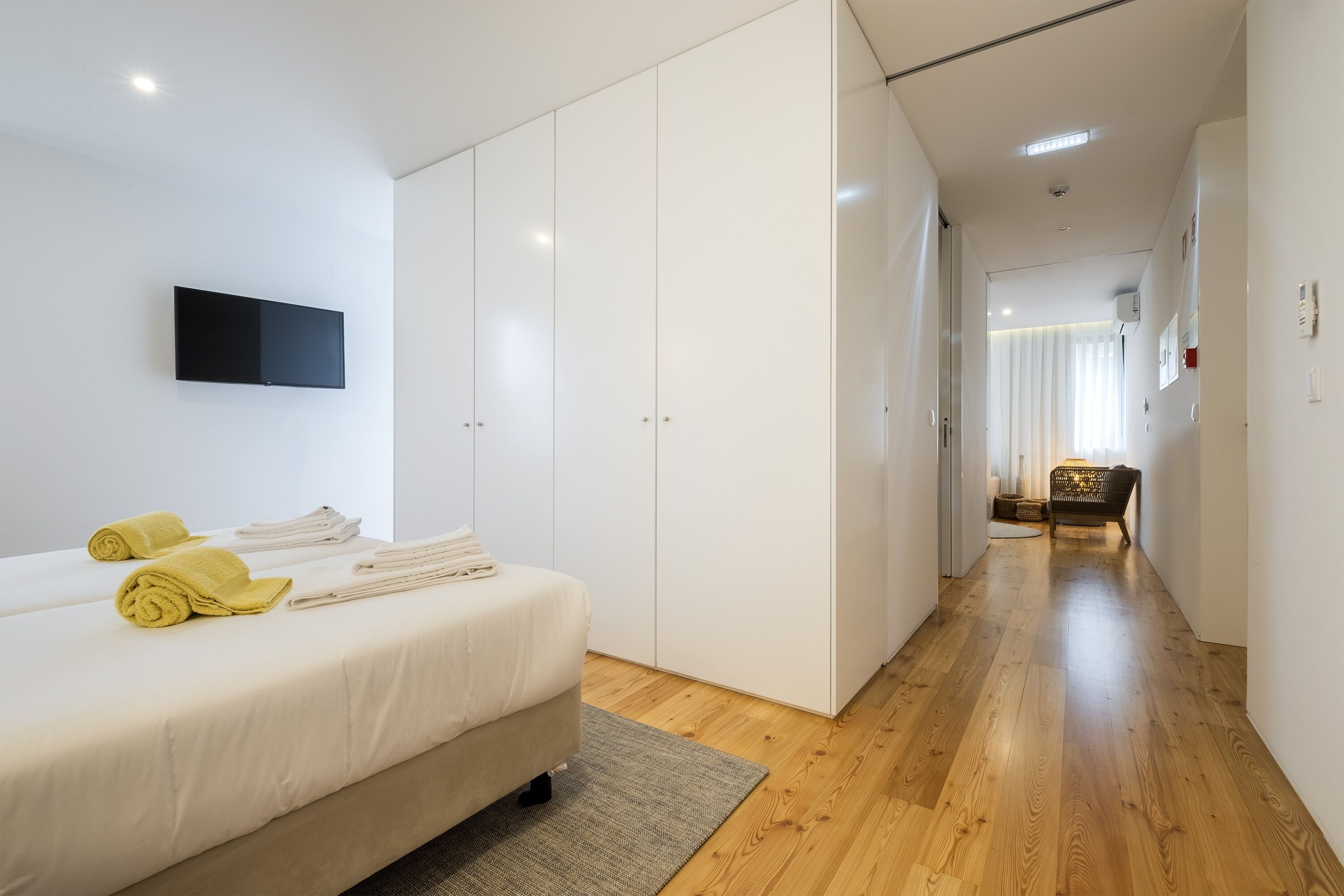 A modern hotel room with a bed, a flat-screen TV, and a wardrobe.