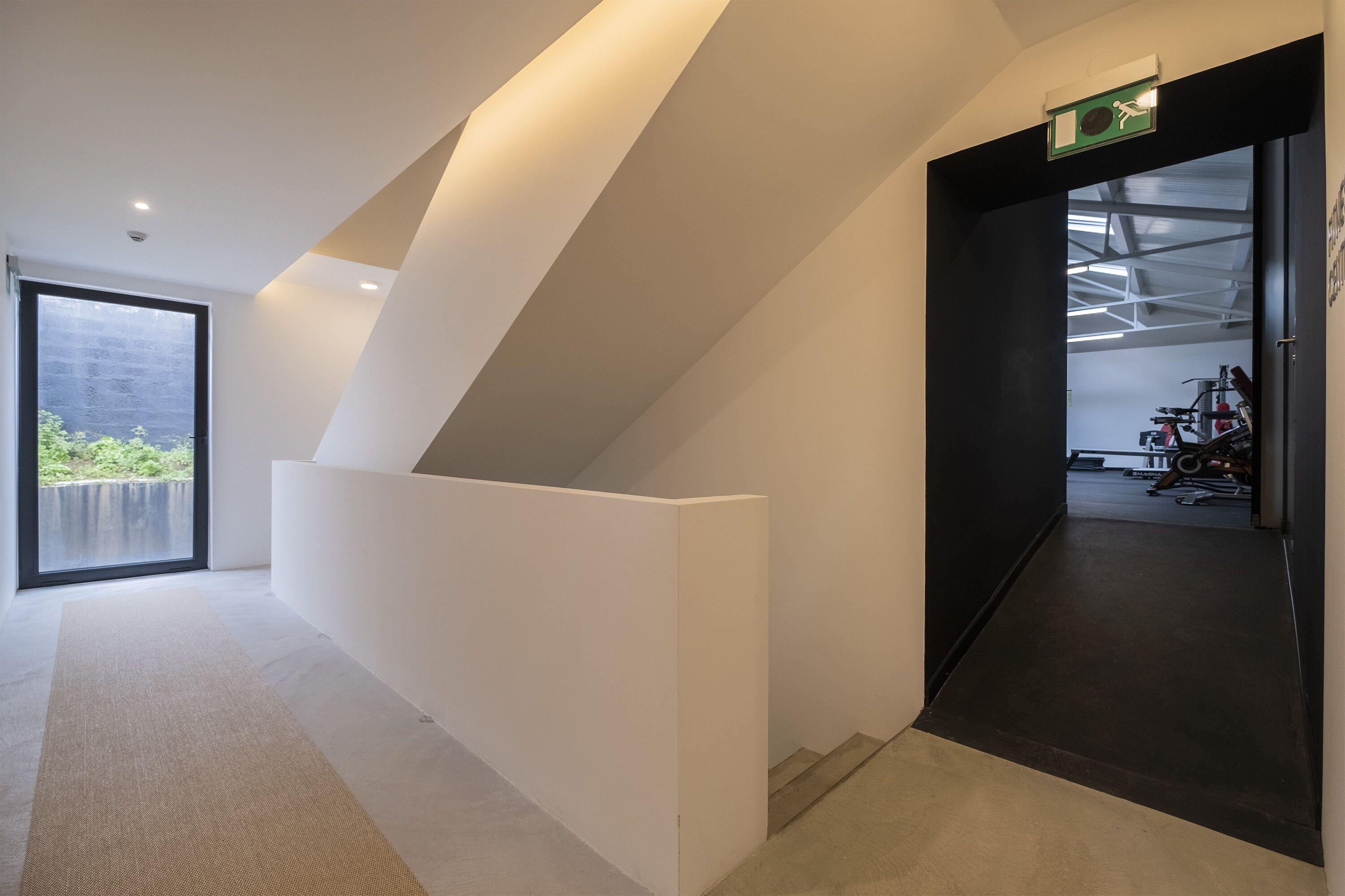 Un hall d’hôtel moderne, doté d’un haut plafond, d’une grande fenêtre et offrant une vue sur l’extérieur.