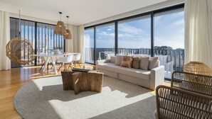 A modern living room with a large window, a white sofa, a dining table, and a hanging chair. - Aqua - Pópulo Eco Village (Ponta Delgada)