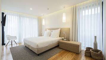 A modern bedroom with a large bed, bedside tables, a chair, and a vase.