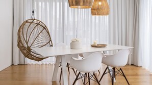 A modern dining area with a white table, wicker chair, and pendant lights. - Aqua - Pópulo Eco Village (Ponta Delgada)