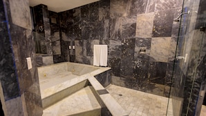 Un bagno moderno con pavimento in marmo, box doccia in vetro e vasca da bagno integrata.