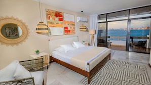 Una moderna camera d'albergo con un letto grande, vista sul mare e un balcone con mobili da esterno.