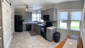 A modern kitchen with grey cabinets, a black refrigerator, a microwave, and a dishwasher.