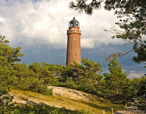 Un faro rodeado de árboles y una colina rocosa.