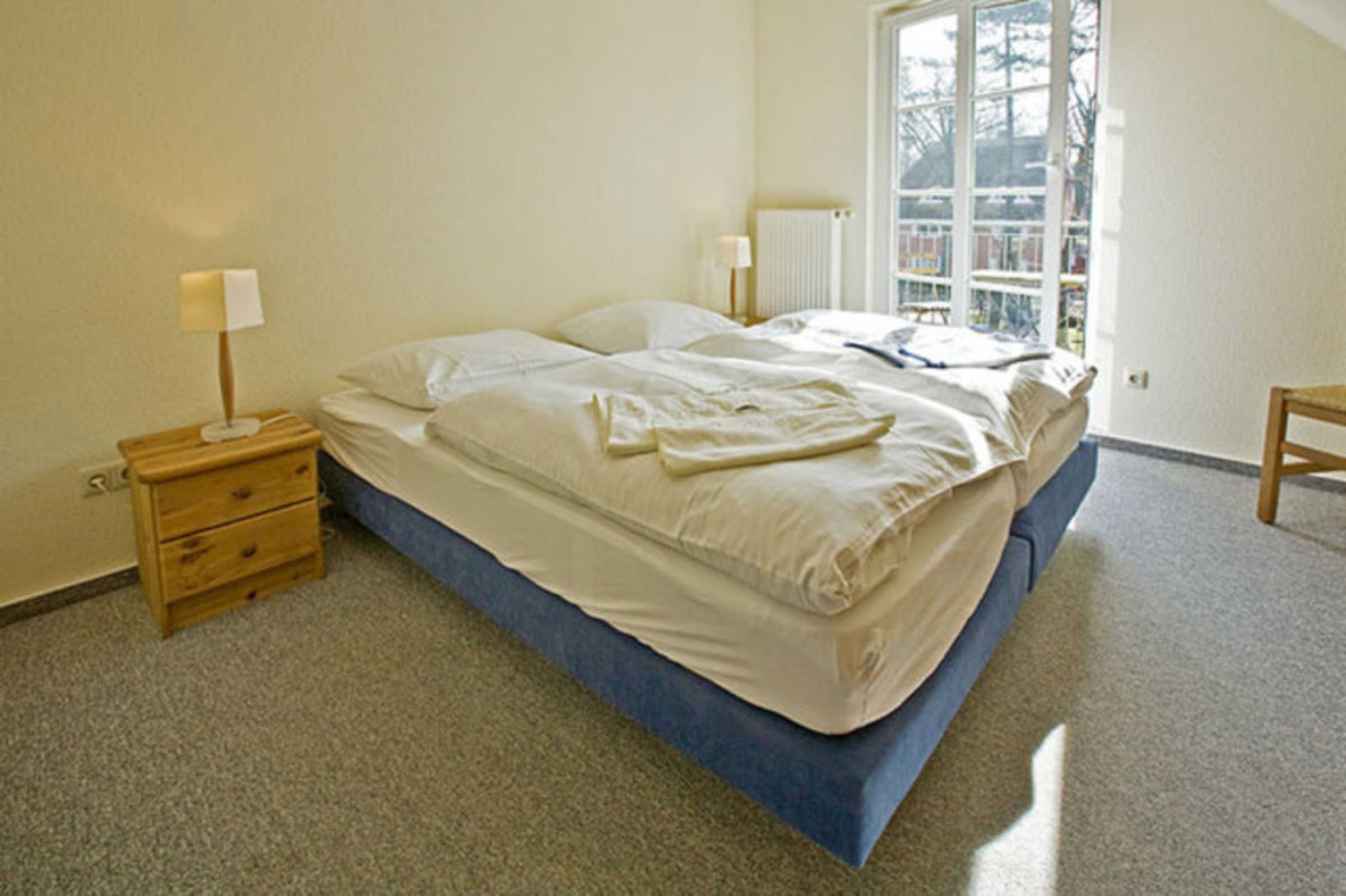 Une chambre à coucher avec un lit, des tables de chevet, une fenêtre et un radiateur.