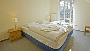 A bedroom with a bed, bedside tables, a window, and a radiator. - House Martha - Kurt - House Martha (Ahrenshoop)