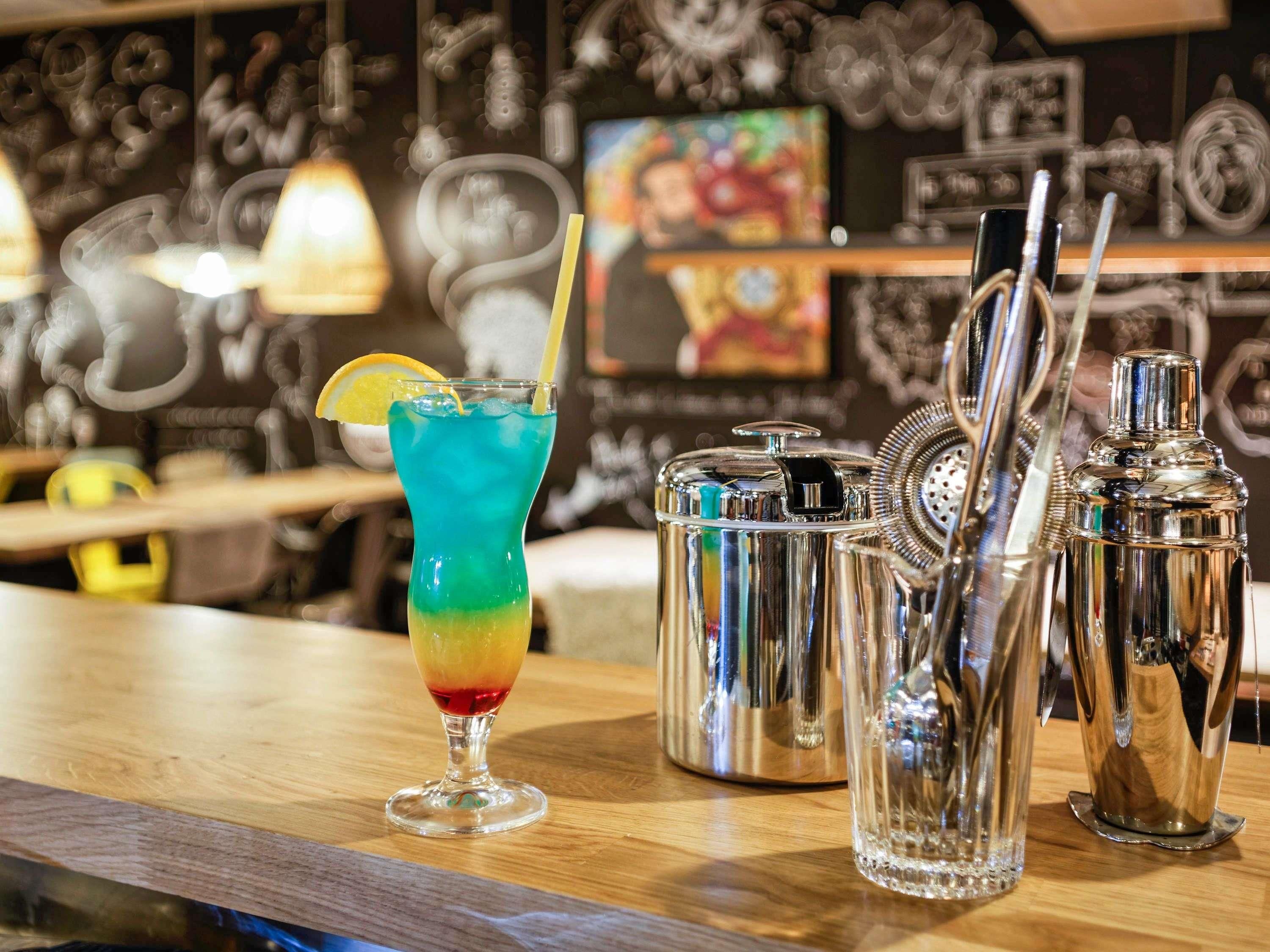 A bar area with a colorful cocktail, a shaker, and a bottle.