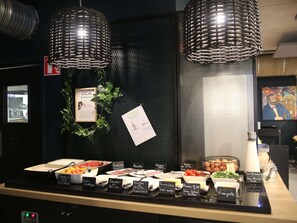 Un mostrador de buffet con diversos alimentos y etiquetas, un certificado enmarco y una guirnalda decorativa.