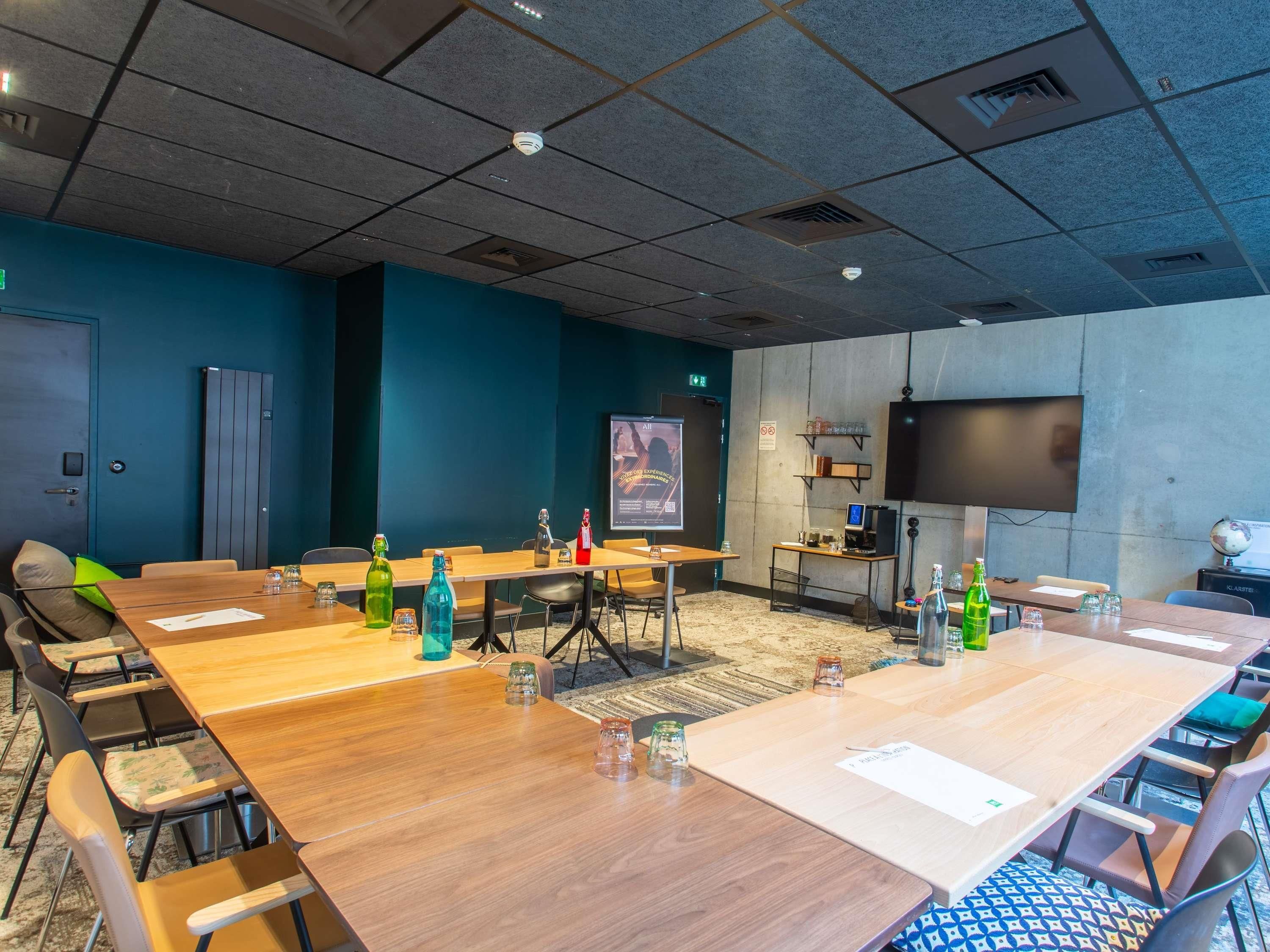 A conference room with a large table, chairs, a projector screen, a television, and a globe.