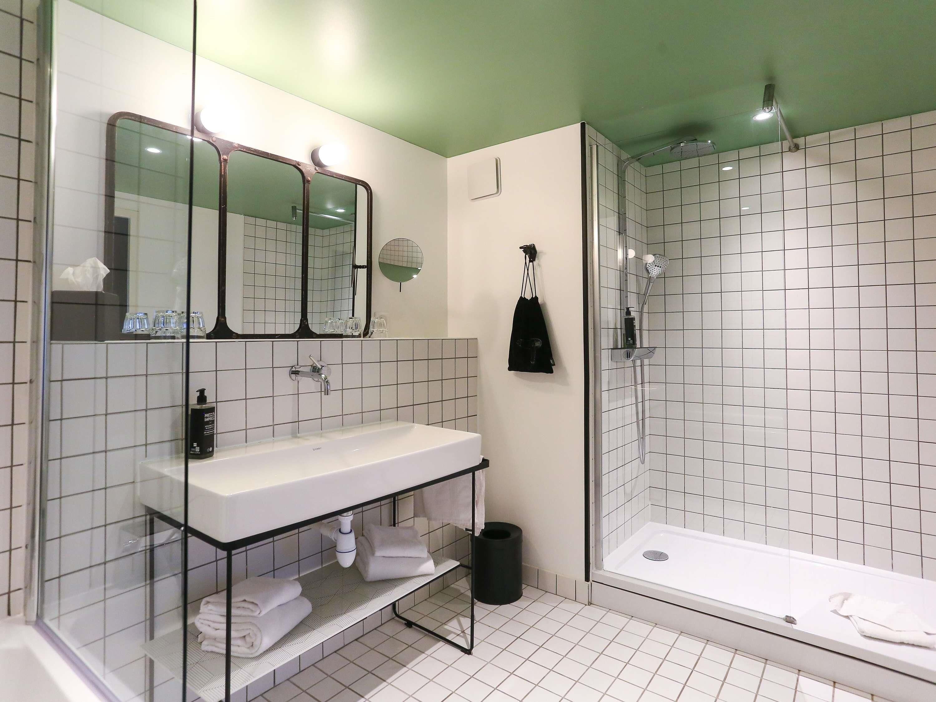 A modern bathroom with a glass-enclosed shower, a white sink with a mirror above it, and a towel rack.