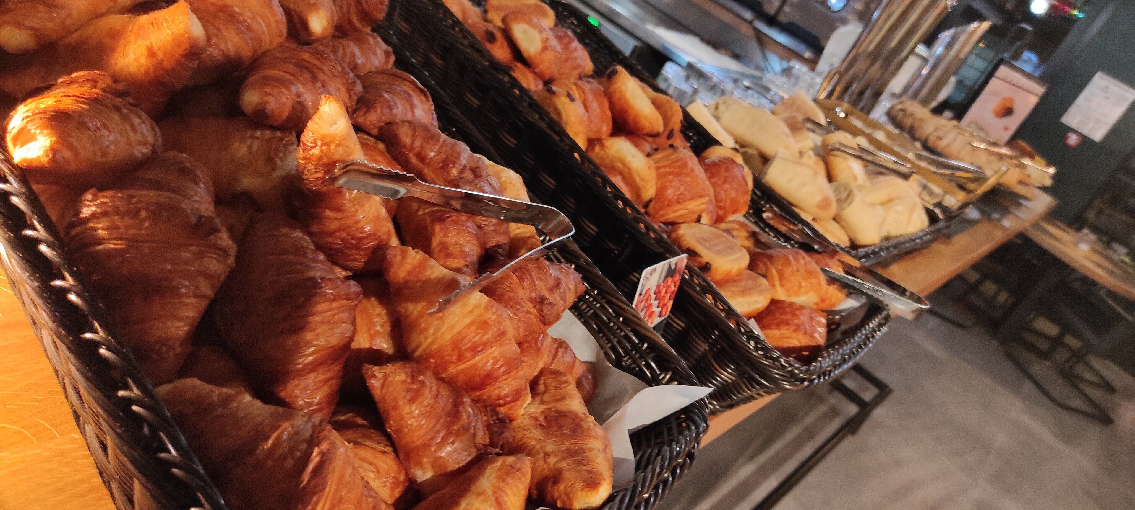 A bakery display with various baked goods, including croissants and bread.