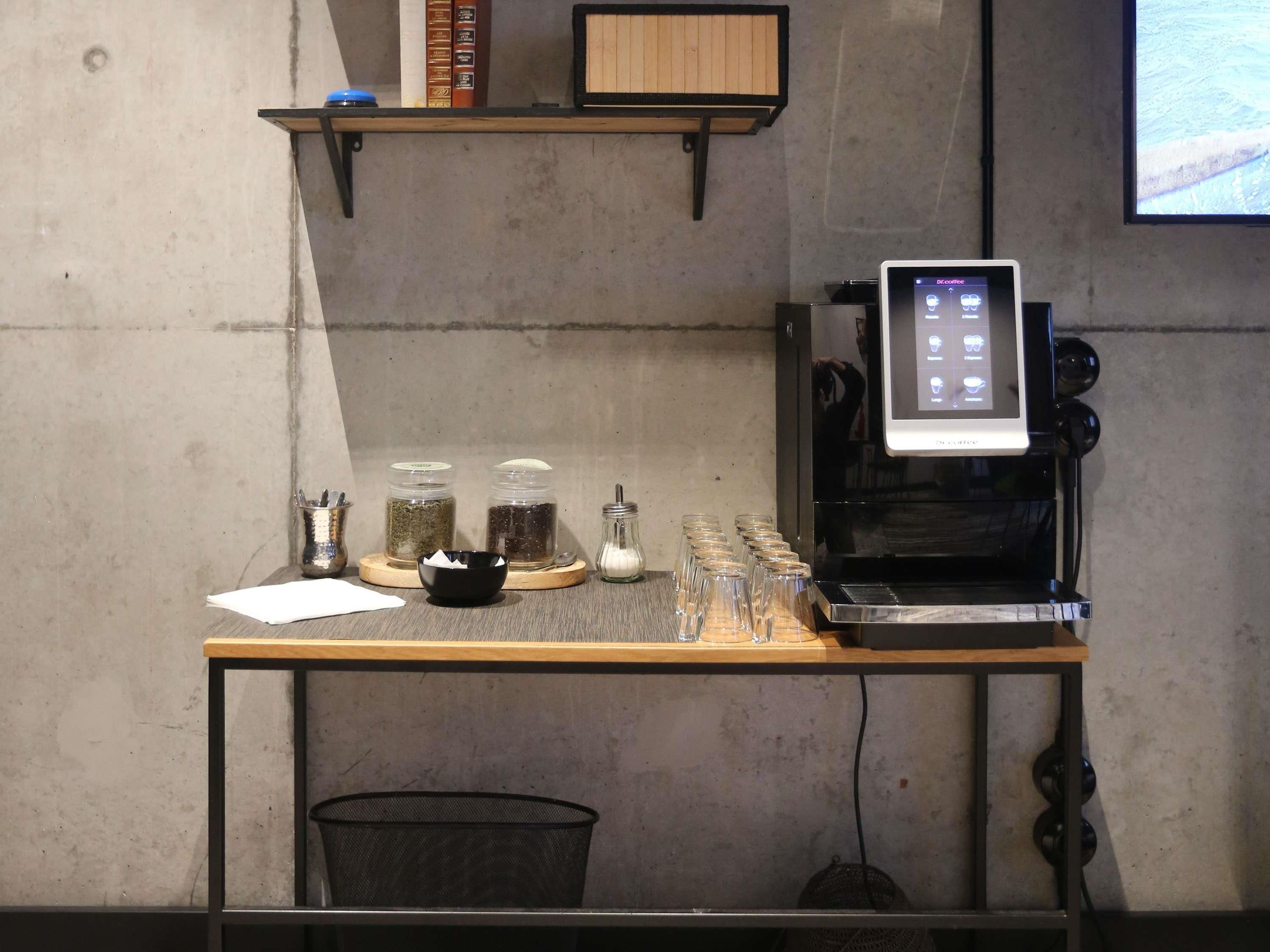 A coffee machine on a table with jars of coffee beans and a bowl.