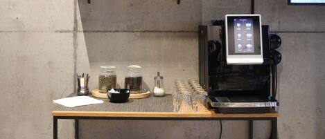 A coffee machine on a table with jars of coffee beans and a bowl.