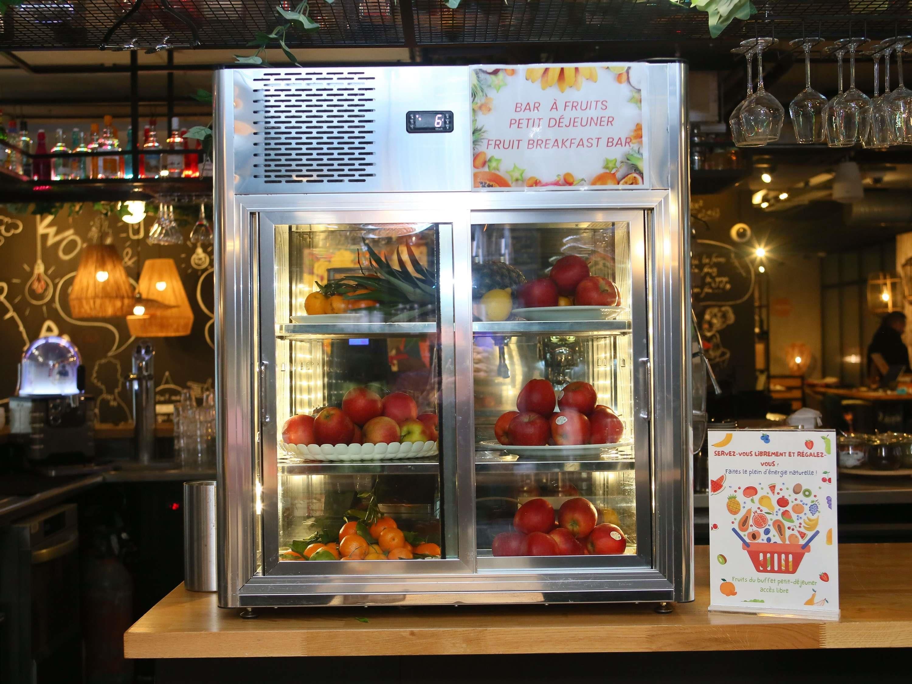 A refrigerated display case with fruits and a sign indicating it's a fruit breakfast bar.