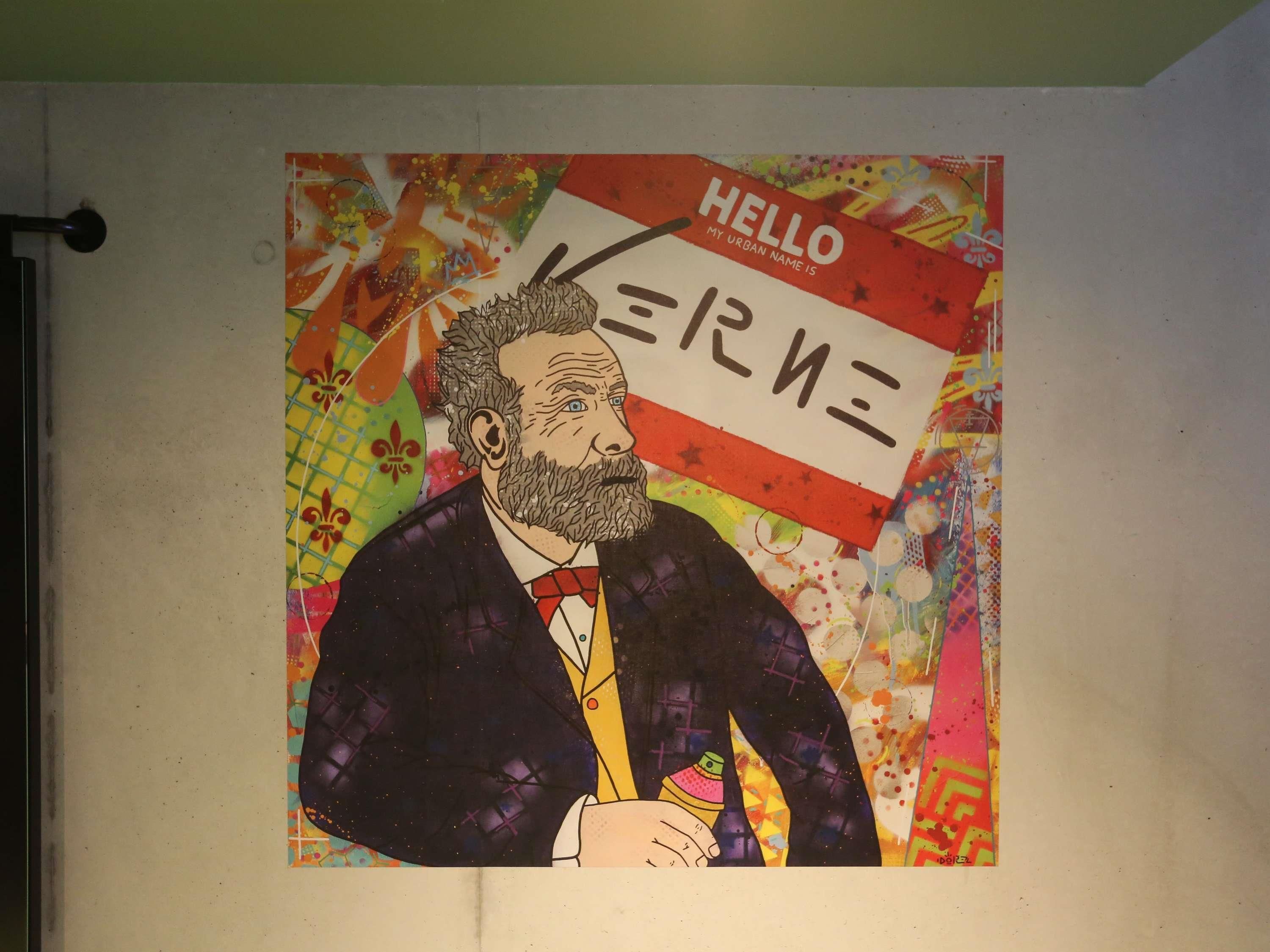 Un cartel colorido con un hombre traje y corbata, un letrero que dice 'HELLO' y diseños abstractos.